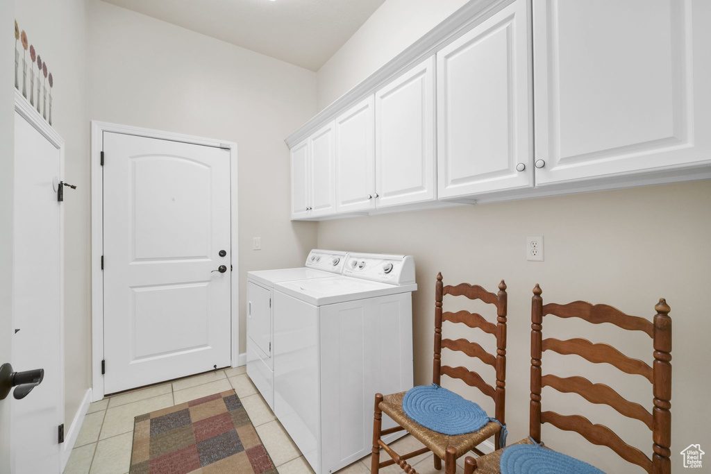 Laundry area with washing machine and dryer, cabinet space, and light tile patterned floors