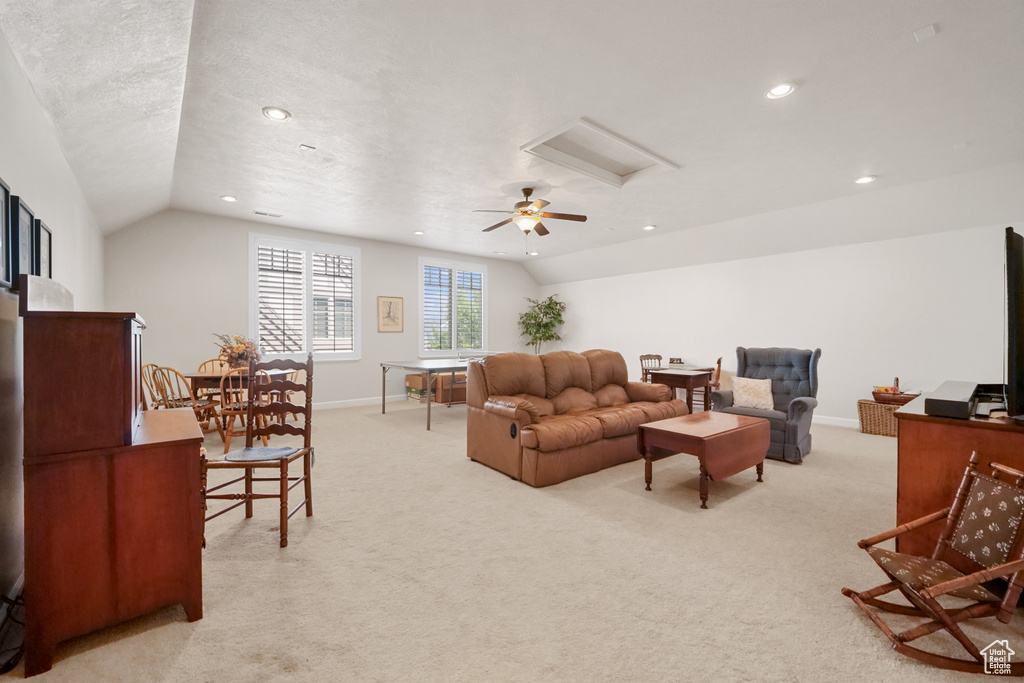 Living area featuring vaulted ceiling, recessed lighting, light colored carpet, and attic access