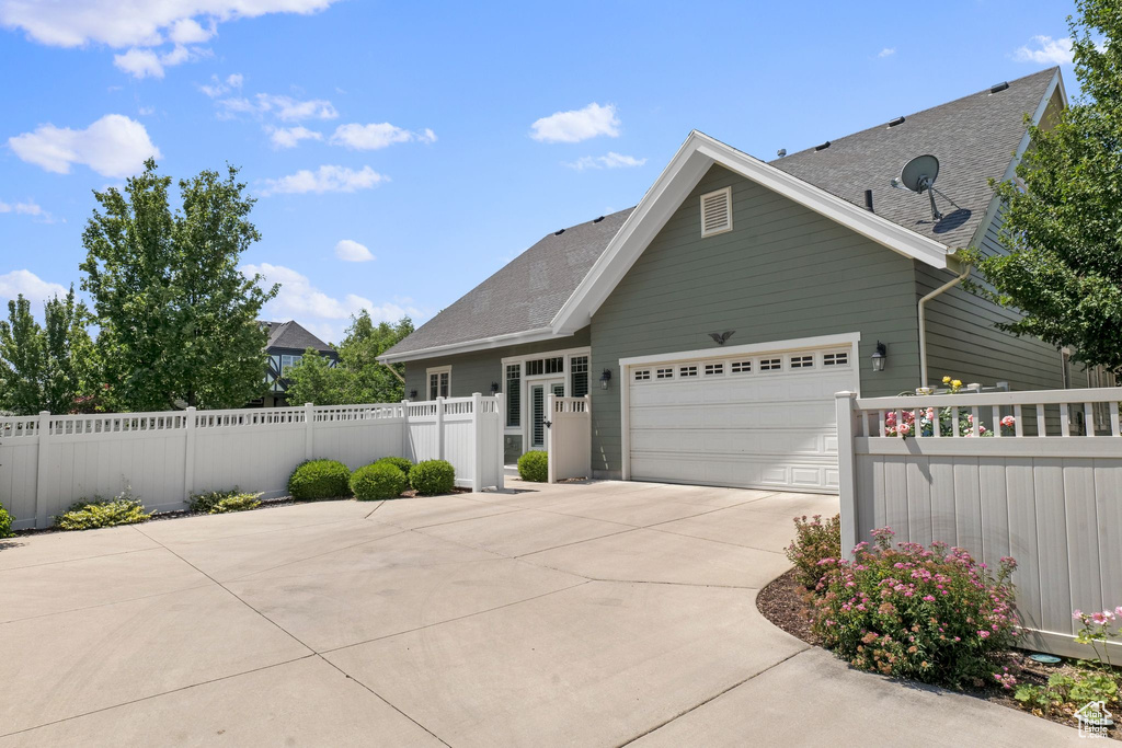 View of front of property featuring a garage, driveway, and roof with shingles