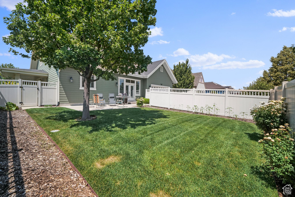 Fenced backyard with a gate, a patio area, and french doors