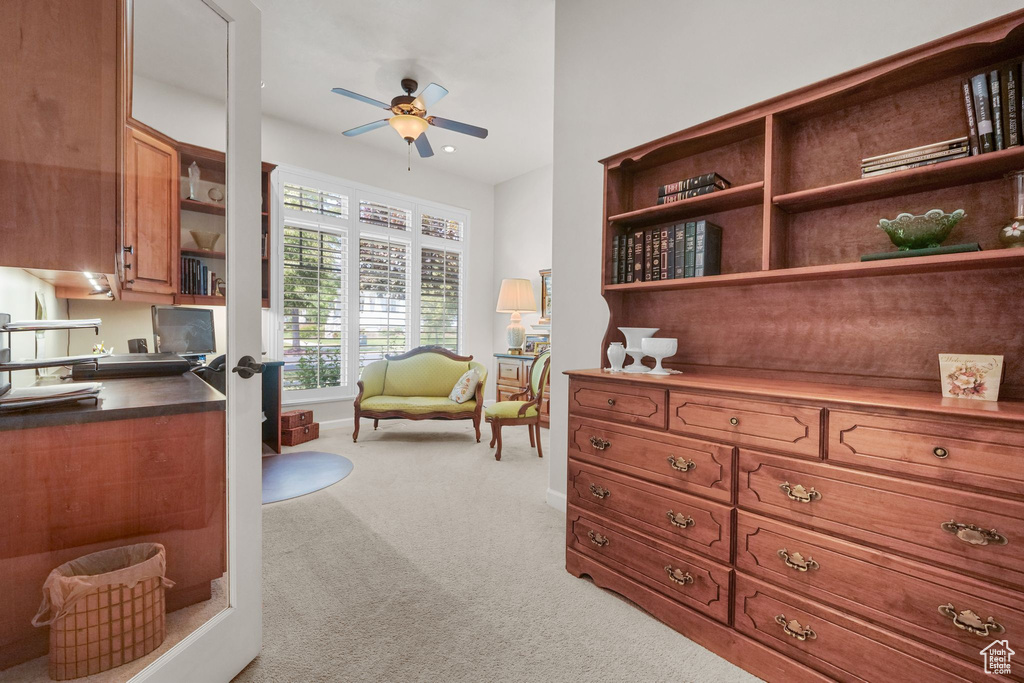Interior space with light colored carpet, a ceiling fan, and a desk
