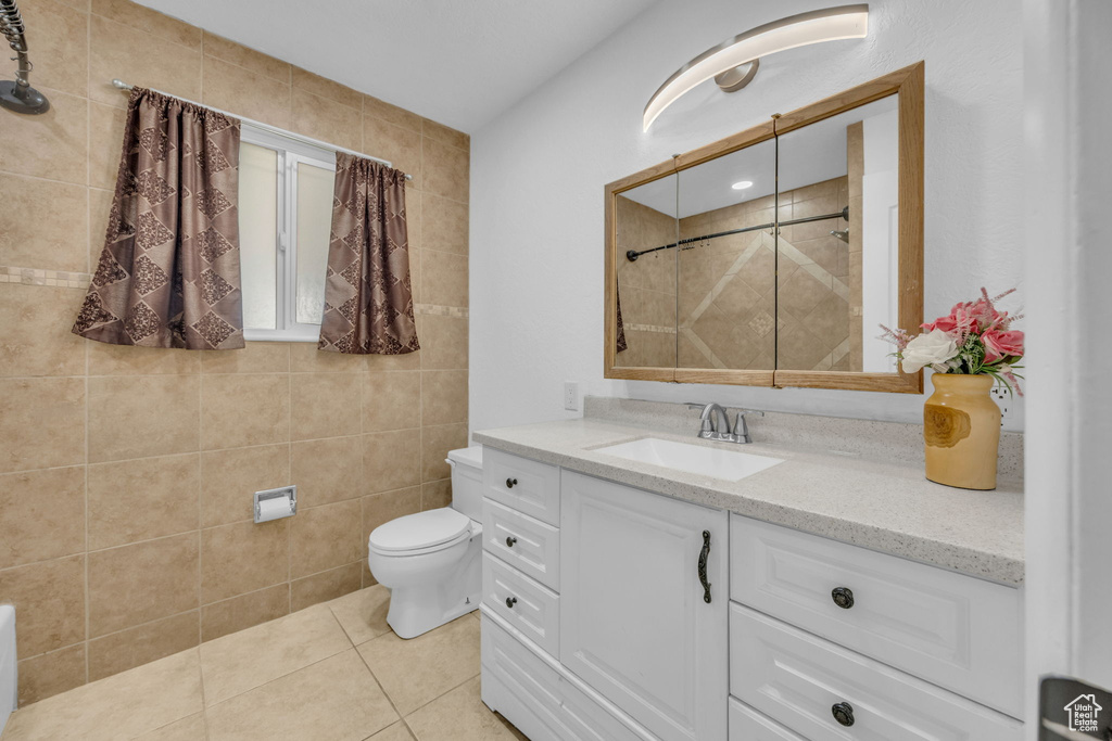 Bathroom with vanity, tile patterned flooring, and a tile shower