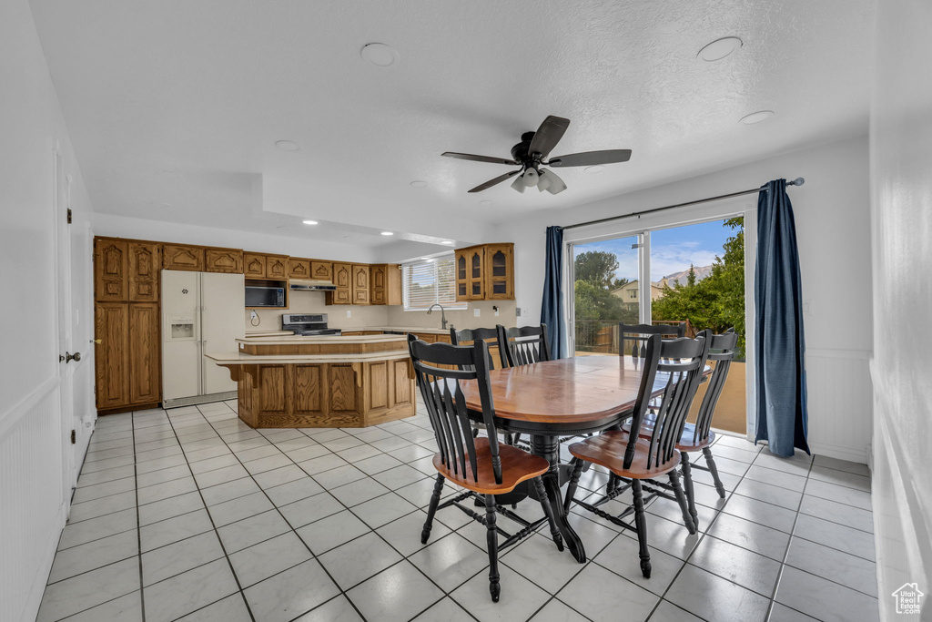 Dining space with recessed lighting, ceiling fan, light tile patterned floors, a textured ceiling, and wainscoting