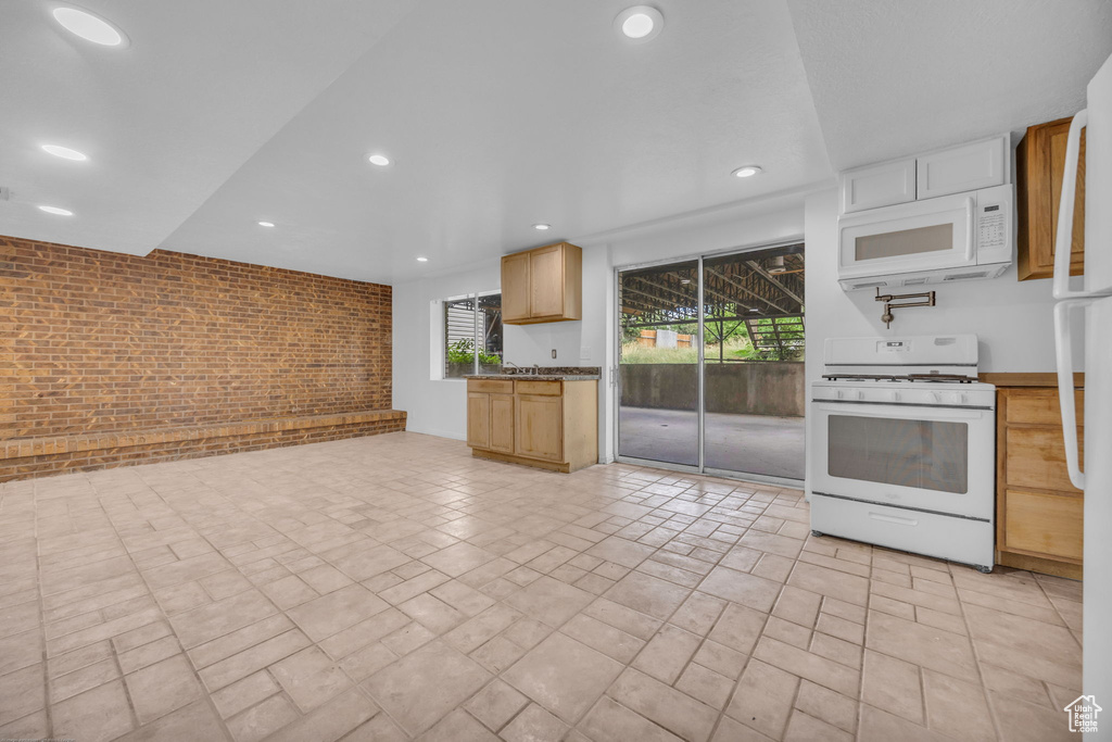 Kitchen featuring white appliances, recessed lighting, and brick wall