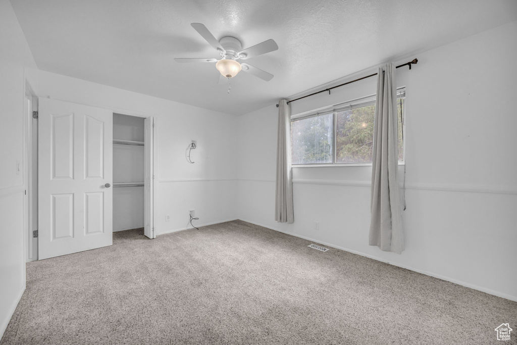 Unfurnished bedroom featuring carpet flooring, a closet, and a ceiling fan