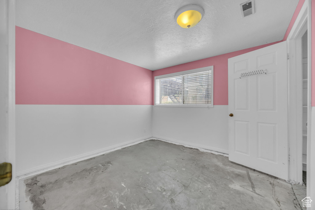 Unfurnished room featuring unfinished concrete flooring and a textured ceiling