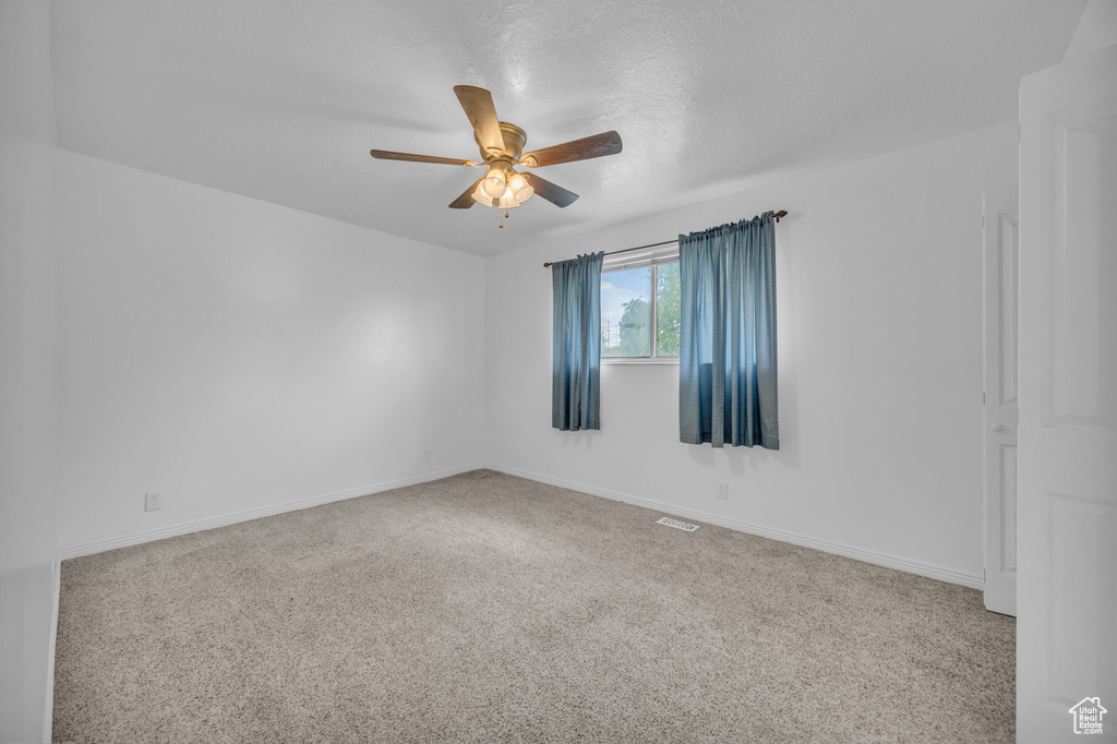 Carpeted empty room with a ceiling fan and baseboards