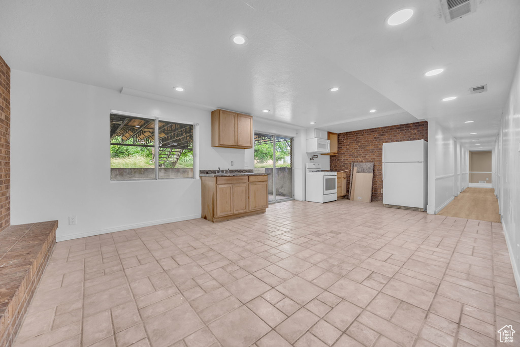 Kitchen with white appliances, brick wall, recessed lighting, open floor plan, and exhaust hood