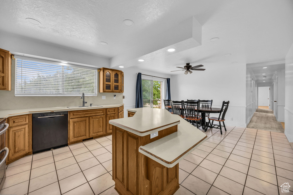 Kitchen with black dishwasher, recessed lighting, light tile patterned floors, light countertops, and brown cabinetry