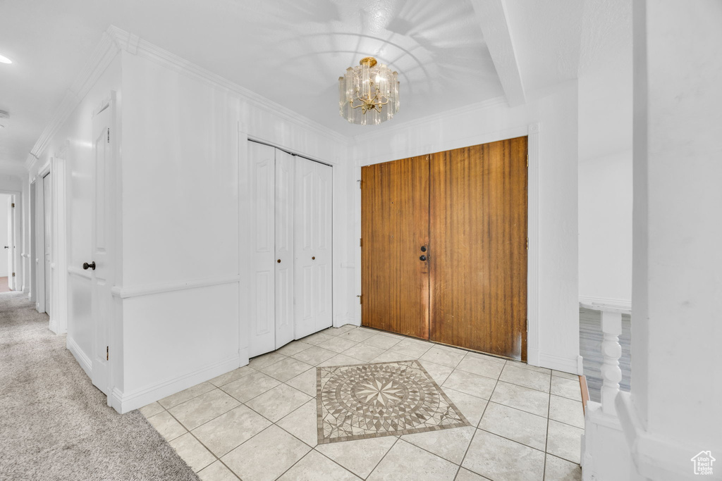 Foyer entrance featuring a chandelier, crown molding, and light tile patterned floors