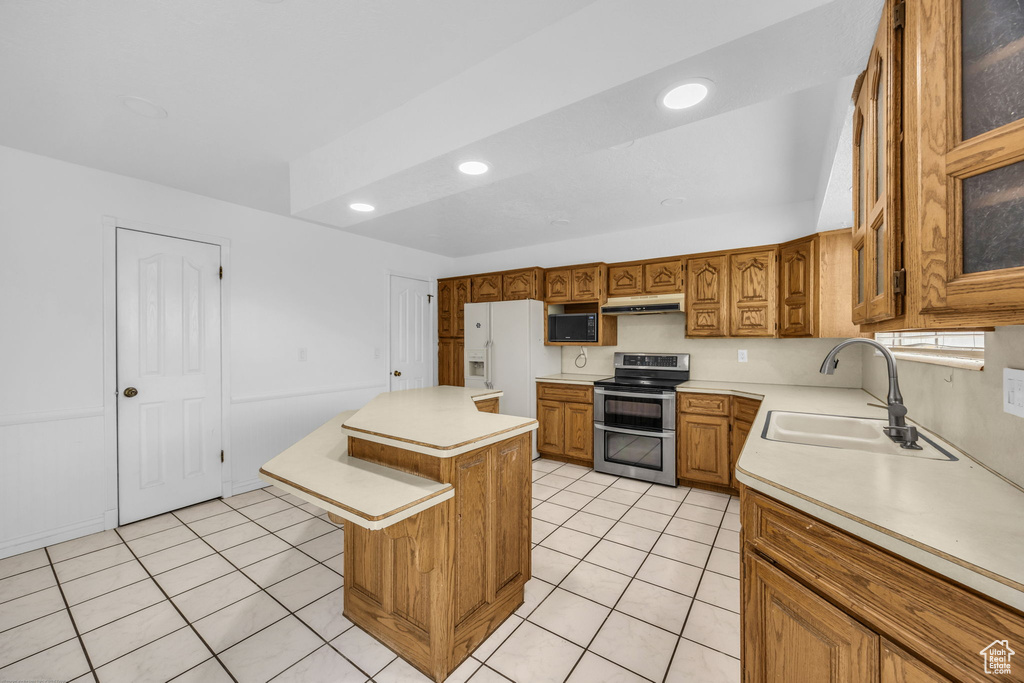 Kitchen with range with two ovens, under cabinet range hood, white refrigerator with ice dispenser, light countertops, and recessed lighting