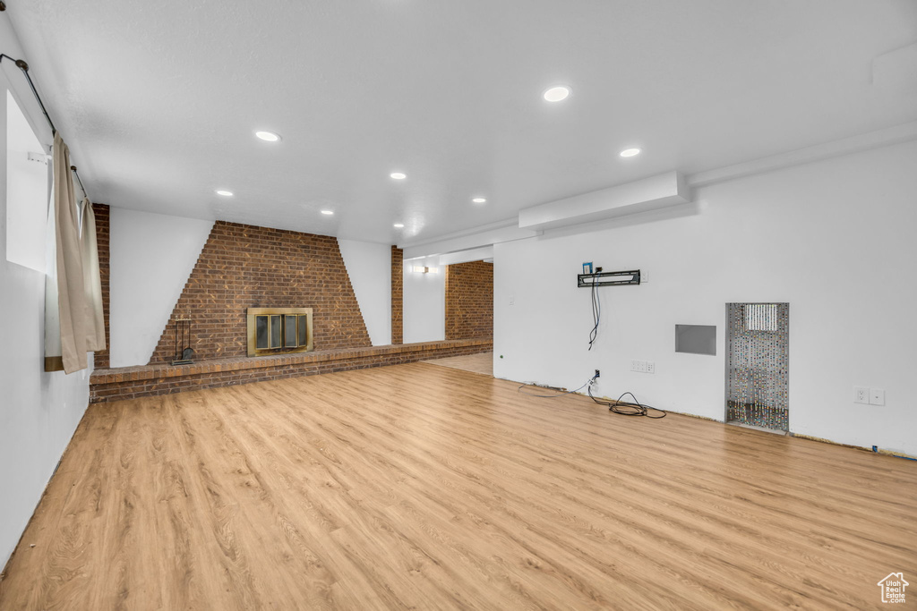 Unfurnished living room featuring a brick fireplace, recessed lighting, and wood finished floors