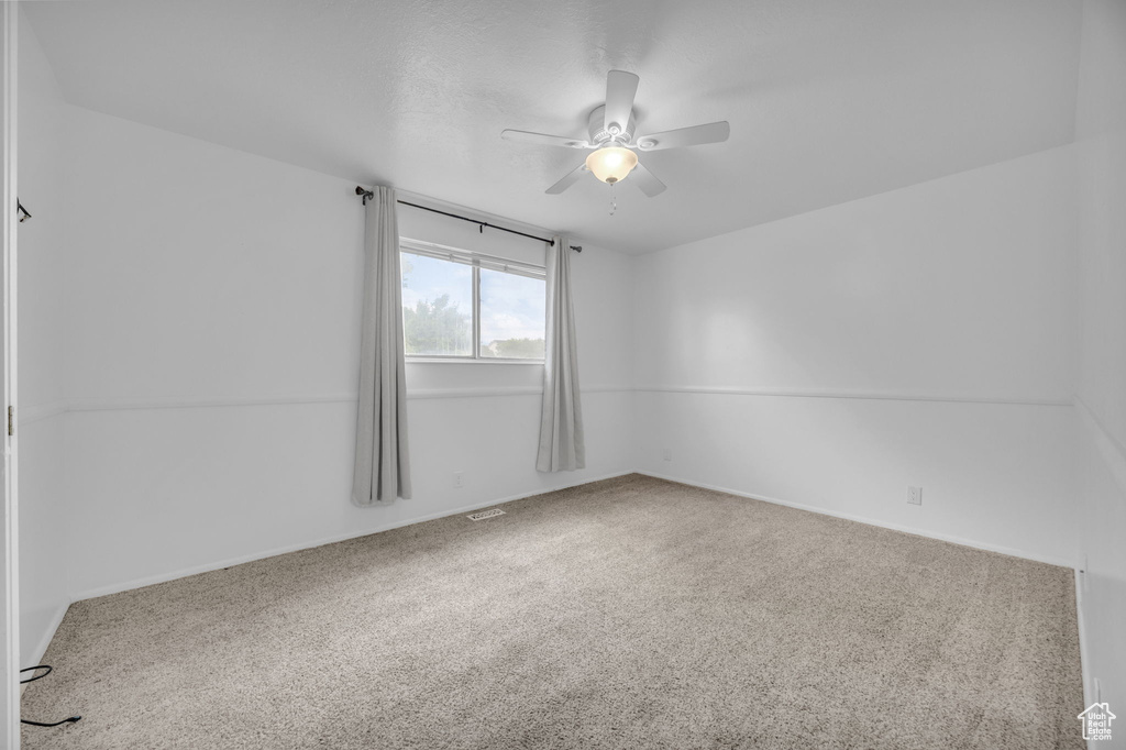 Carpeted spare room with a ceiling fan