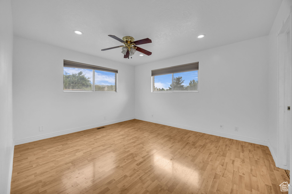 Empty room featuring healthy amount of natural light, light wood-style flooring, ceiling fan, and recessed lighting