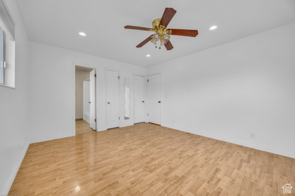Unfurnished bedroom with light wood-type flooring, multiple closets, recessed lighting, and a ceiling fan
