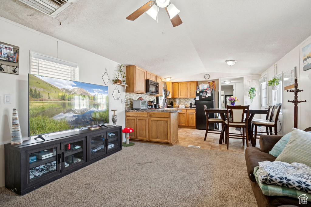 Living room with lofted ceiling, light colored carpet, and a ceiling fan