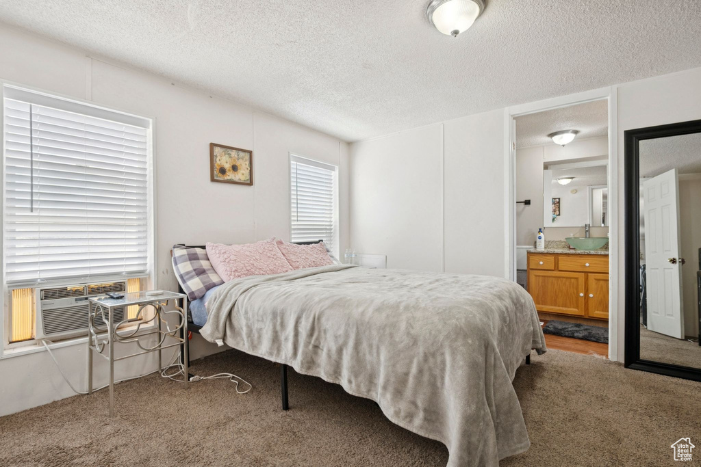 Bedroom featuring carpet, a textured ceiling, ensuite bath, and cooling unit