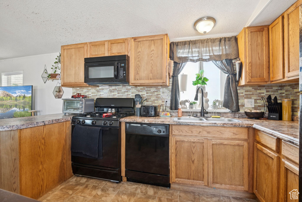 Kitchen with black appliances, a textured ceiling, and tasteful backsplash