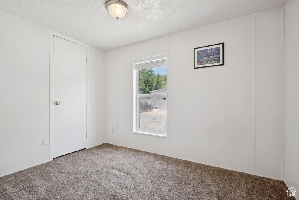 Carpeted spare room featuring a textured ceiling