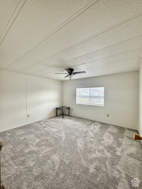 Empty room featuring carpet floors, ceiling fan, and a textured ceiling