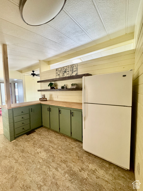 Kitchen featuring green cabinets, freestanding refrigerator, wooden counters, open shelves, and a textured ceiling