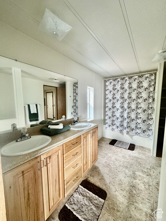 Bathroom featuring double vanity, a textured ceiling, tile patterned floors, and a shower with shower curtain