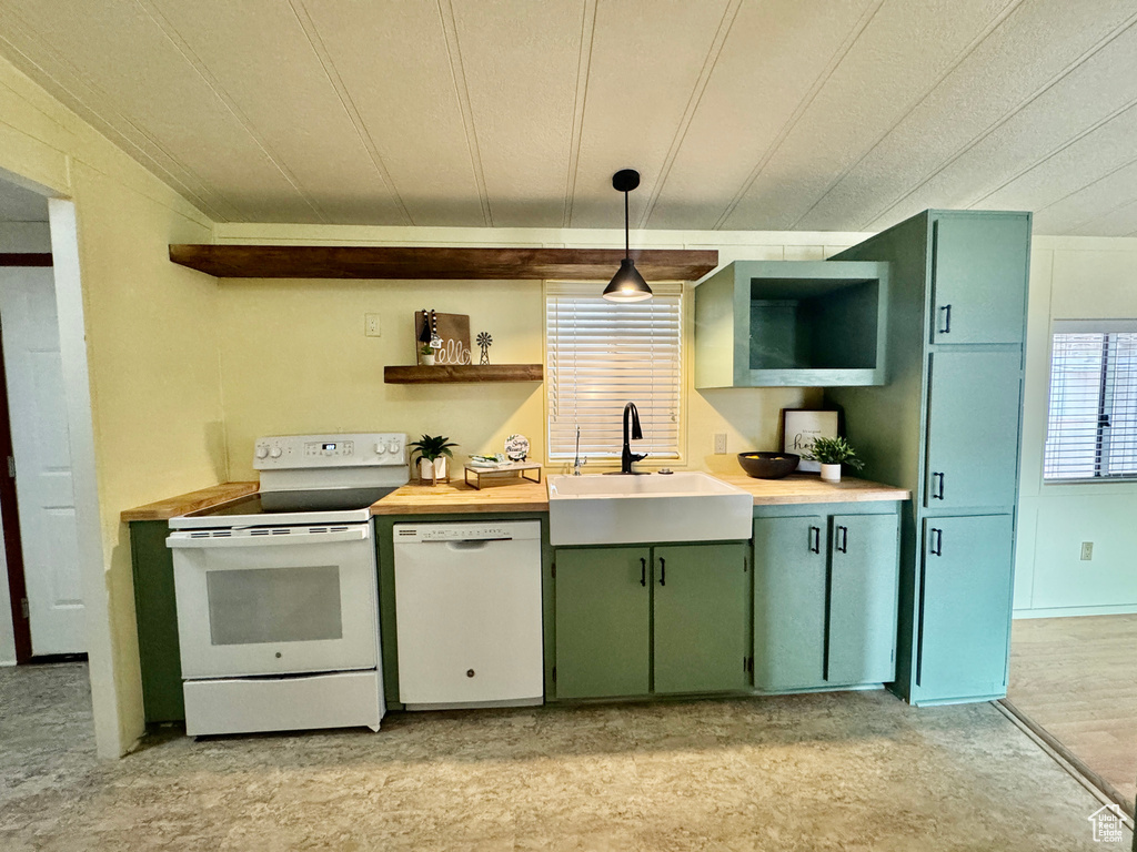 Kitchen featuring white appliances, green cabinetry, open shelves, decorative light fixtures, and wooden counters