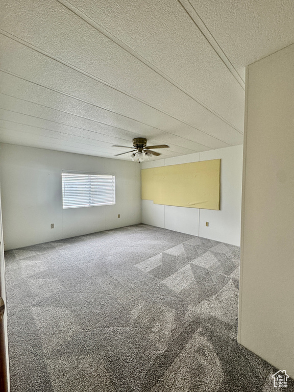Carpeted spare room with a textured ceiling and ceiling fan