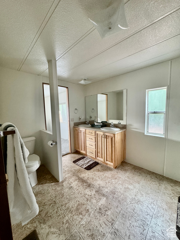Bathroom with double vanity, tile patterned floors, and a textured ceiling