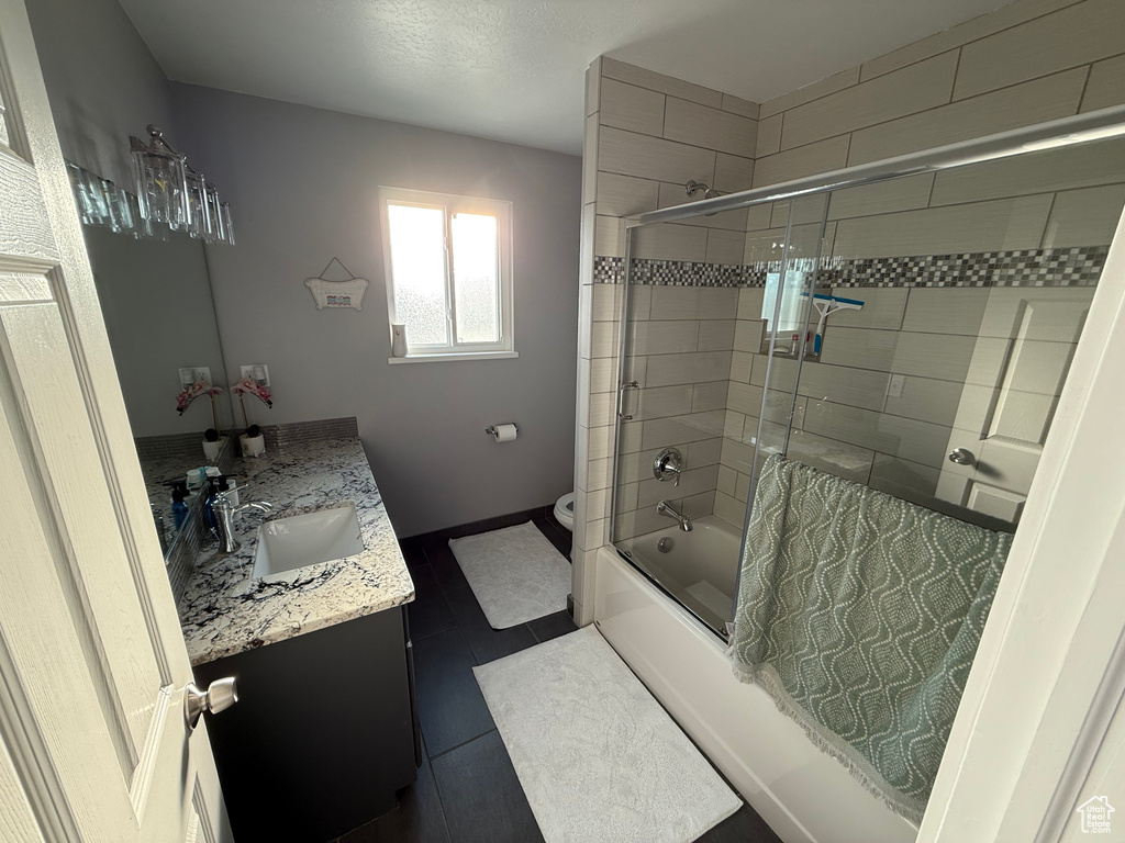Full bath with vanity, combined bath / shower with glass door, and tile patterned floors