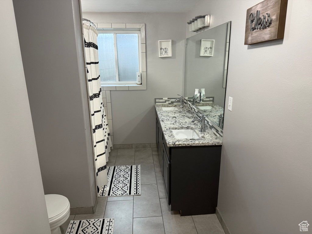 Full bath with double vanity, tile patterned flooring, and a shower with shower curtain