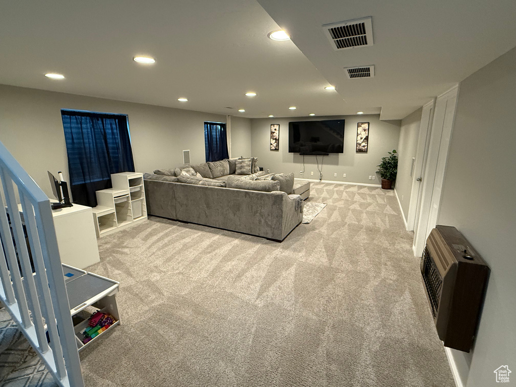 Living room featuring light colored carpet, recessed lighting, heating unit, and stairway