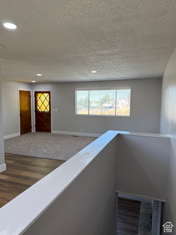 Hallway featuring wood finished floors, a textured ceiling, and recessed lighting