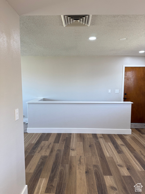 Corridor featuring dark wood finished floors and a textured ceiling