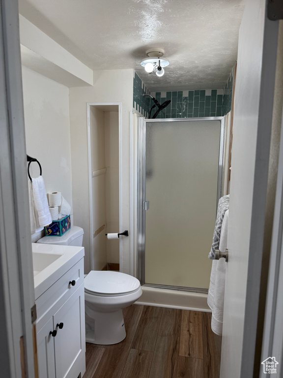 Bathroom with a stall shower, wood finished floors, and vanity