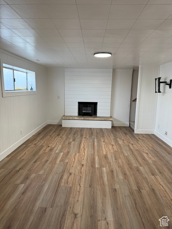Unfurnished living room featuring wood finished floors and a large fireplace