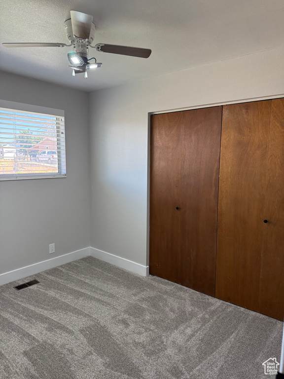 Unfurnished bedroom featuring a closet, carpet flooring, and ceiling fan