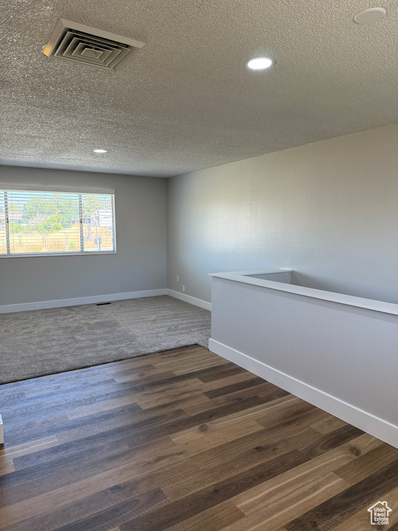 Unfurnished room with a textured ceiling, recessed lighting, and dark wood-style floors