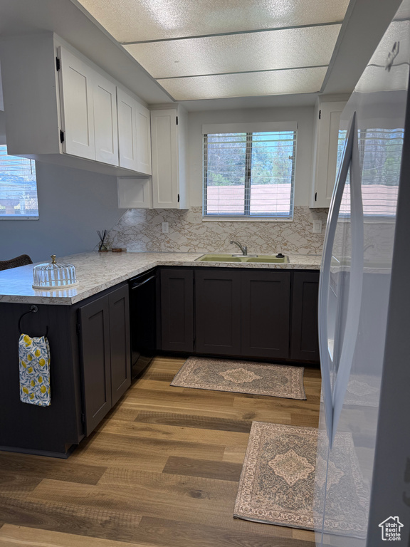 Kitchen featuring freestanding refrigerator, dishwasher, white cabinetry, light wood finished floors, and decorative backsplash