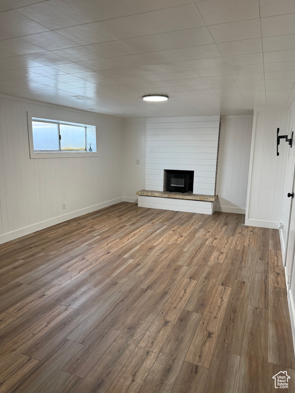 Unfurnished living room featuring wood finished floors and a brick fireplace