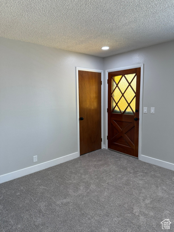 Empty room with carpet flooring and a textured ceiling