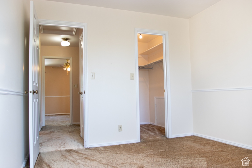 Unfurnished bedroom with attic access, a walk in closet, and carpet