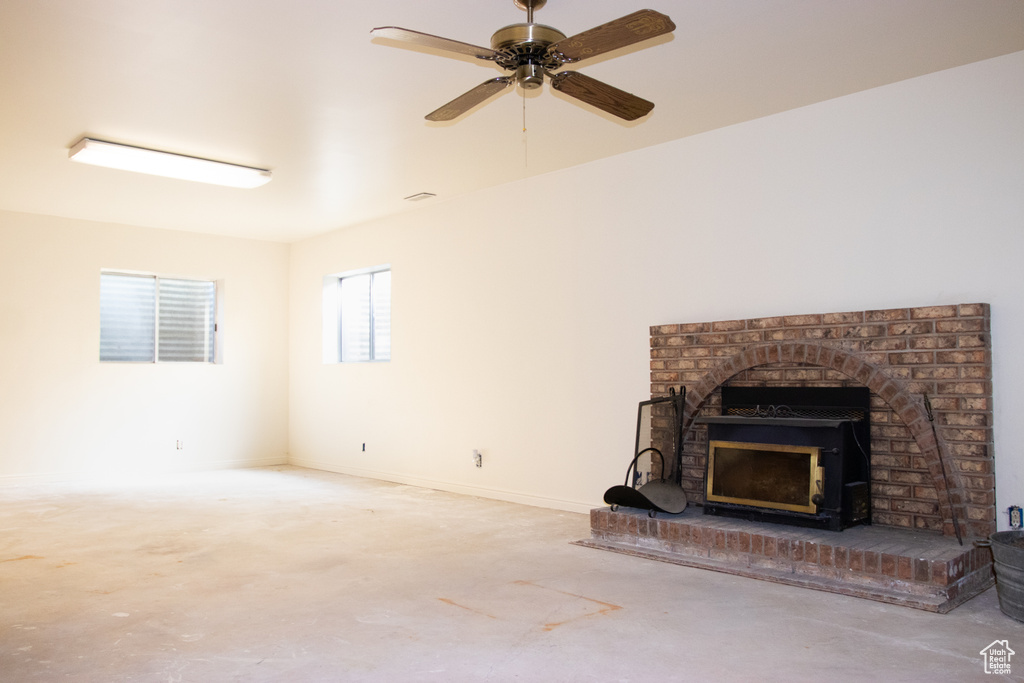Unfurnished living room featuring a brick fireplace and ceiling fan