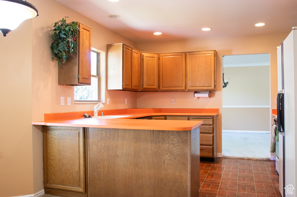 Kitchen featuring recessed lighting, a peninsula, light countertops, and brick patterned flooring