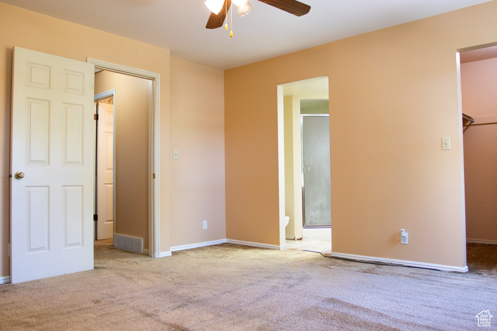 Unfurnished bedroom featuring carpet flooring, a walk in closet, and a ceiling fan