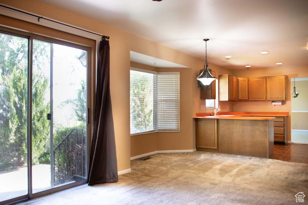 Kitchen featuring carpet floors, hanging light fixtures, a peninsula, light countertops, and recessed lighting
