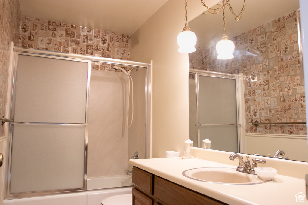 Bathroom featuring wallpapered walls, vanity, and enclosed tub / shower combo