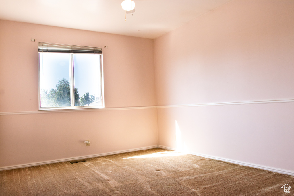 Carpeted empty room with baseboards and a ceiling fan