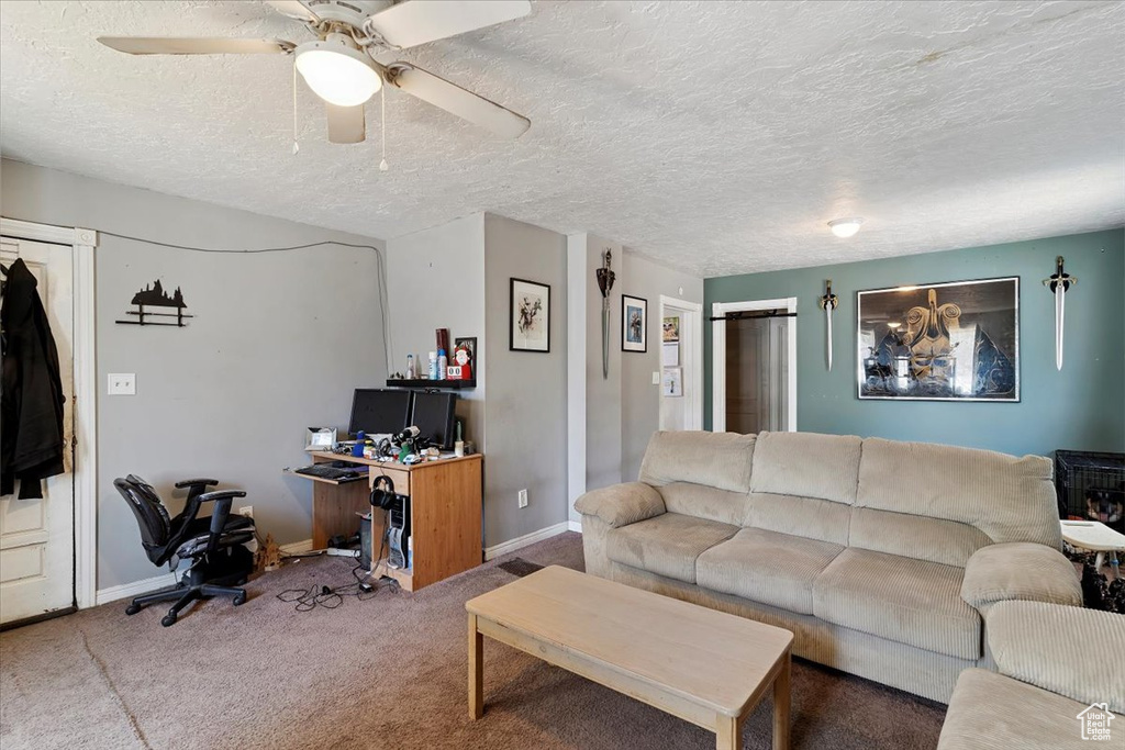 Carpeted living room with a desk, a ceiling fan, and a textured ceiling