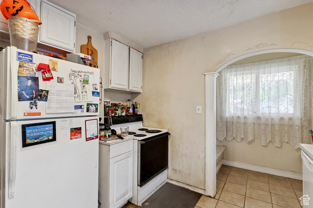 Kitchen with white appliances, white cabinets, light tile patterned floors, and light countertops